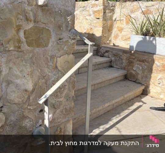 מעקה מתכת מותקן לצד מדרגות אבן חיצוניות